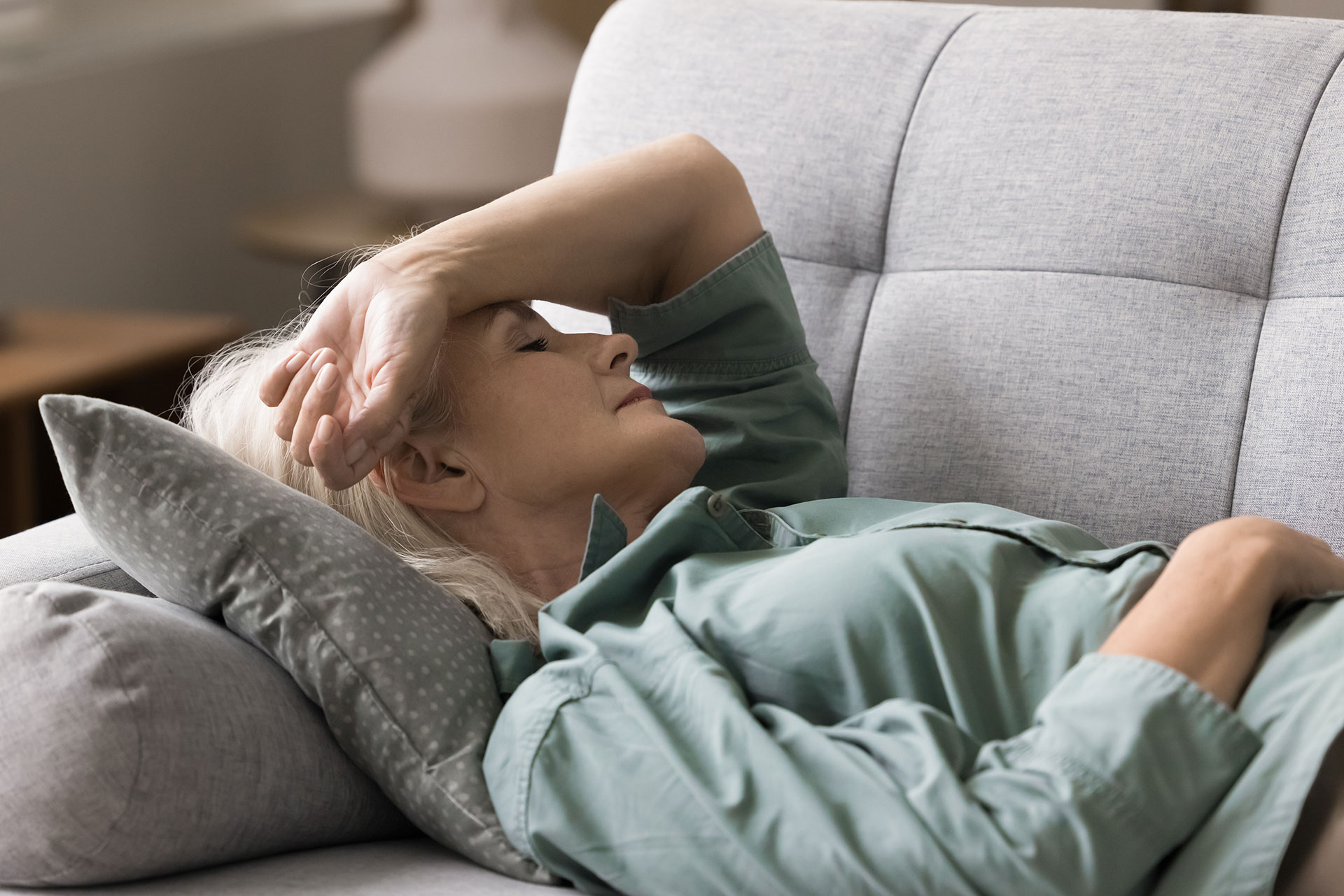 A woman lying on her side on a couch with her hand resting on her head.